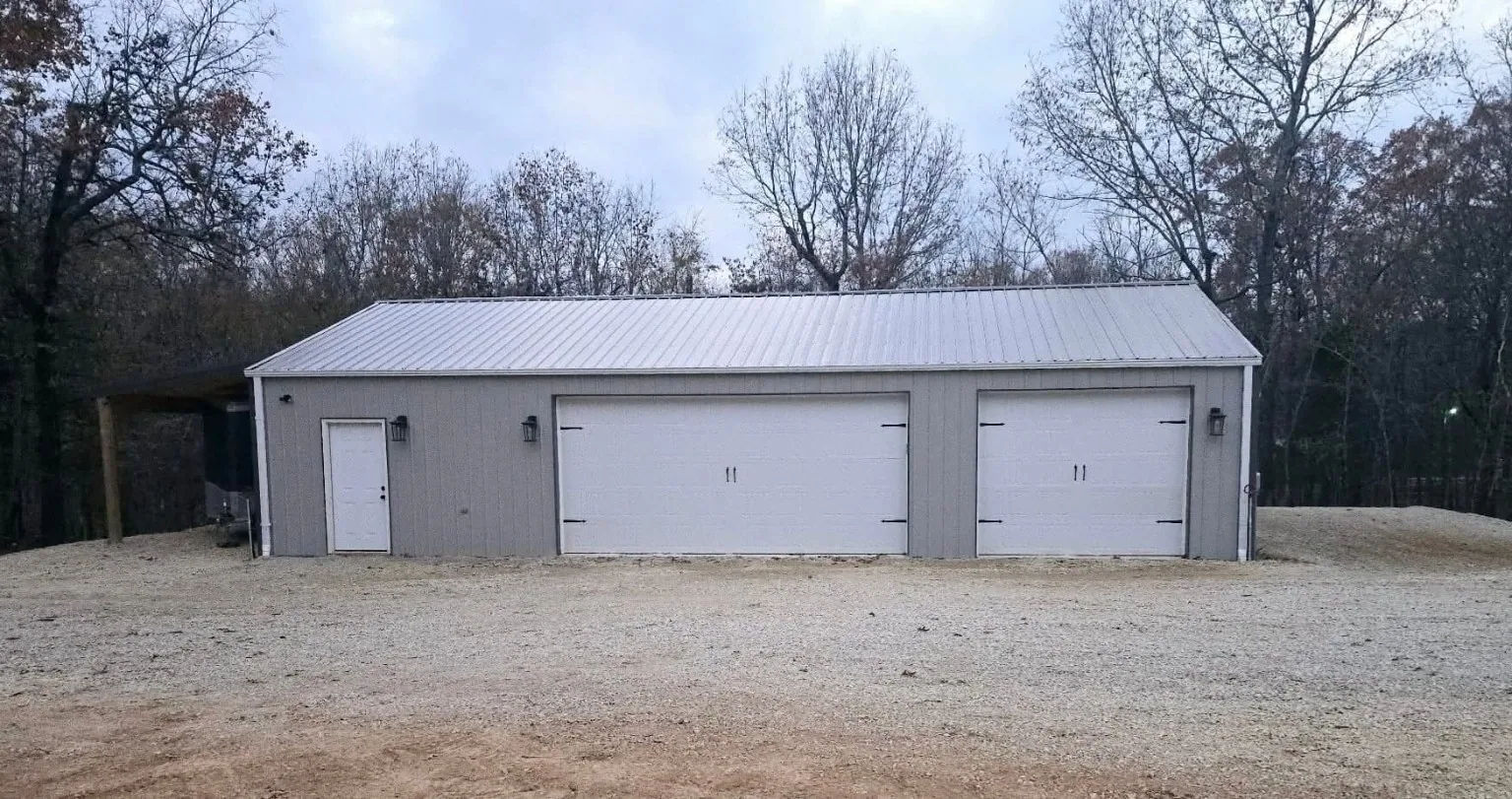 Detached metal garage with white overhead doors
